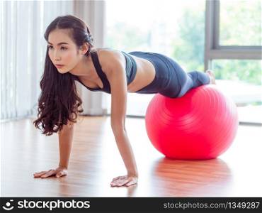 Woman doing pilates exercises with fit ball in fitness gym or yoga class. Healthy lifestyle concept.