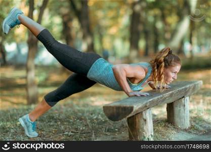 Woman doing push ups in the park, in the fall in Public Park