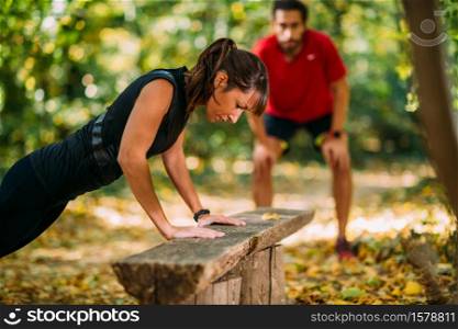 Woman doing push-ups in the park with personal trainer. Exercising in the Park