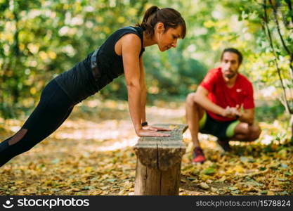 Woman doing push-ups in the park with personal trainer. Exercising in the Park