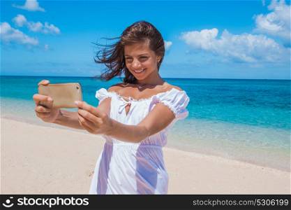 Woman doing selfie on beach. Beautiful happy woman doing selfie with phone on tropical sea beach