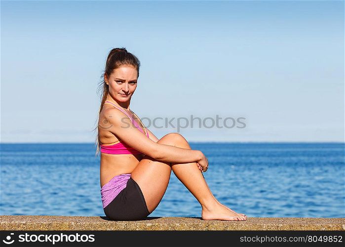 Woman doing sports exercises outdoors by seaside. Woman doing sports outdoors. Fitness girl in sportswear on seaside exercising keep her body muscles fit