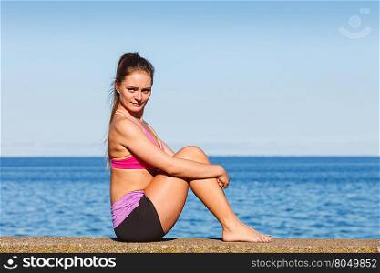 Woman doing sports exercises outdoors by seaside. Woman doing sports outdoors. Fitness girl in sportswear on seaside exercising keep her body muscles fit