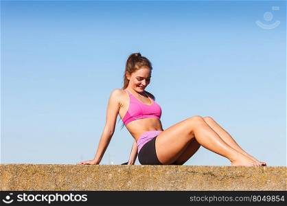Woman doing sports exercises outdoors by seaside. Woman doing sports outdoors. Fitness girl in sportswear exercising keep her body muscles fit against blue sky