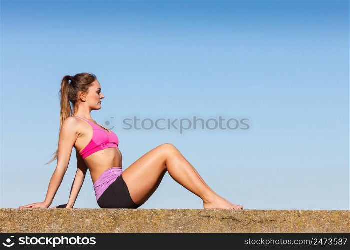 Woman doing sports outdoors. Fitness girl in sportswear exercising keep her body muscles fit against blue sky. Woman doing sports exercises outdoors by seaside