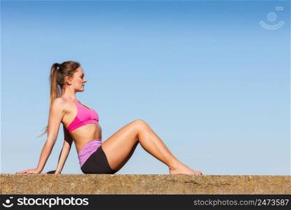 Woman doing sports outdoors. Fitness girl in sportswear exercising keep her body muscles fit against blue sky. Woman doing sports exercises outdoors by seaside