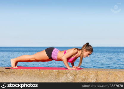 Woman doing sports outdoors. Fitness girl in sportswear on seaside exercising keep her body muscles fit. Woman doing sports exercises outdoors by seaside