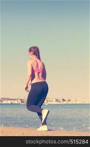 Woman doing sports outdoors. Fitness girl in sportswear on seaside exercising keep her body muscles fit. Woman doing sports exercises outdoors by seaside