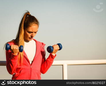 Woman doing sports outdoors with dumbbells. Woman doing sports outdoors with dumbbells. Fit fitness girl in sportswear on seaside exercising