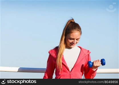 Woman doing sports outdoors with dumbbells. Woman doing sports outdoors with dumbbells. Fit fitness girl in sportswear exercising against sky