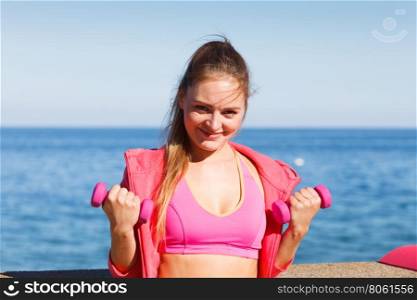 Woman doing sports outdoors with dumbbells. Woman doing sports outdoors with dumbbells. Fit fitness girl in sportswear on seaside exercising