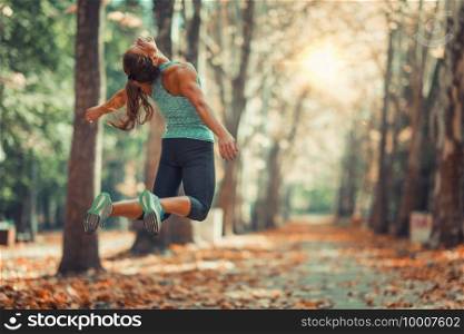 Woman Doing Star Jump Outdoors in The Fall, in Public Park
