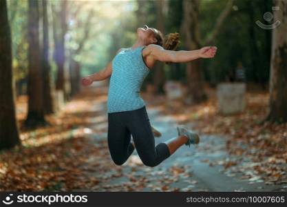 Woman Doing Star Jump Outdoors in The Fall, in Public Park