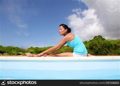 Woman doing stretching exercises by a pool