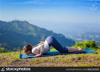 Woman doing yoga asana Ashtangasana eight-limbed pose outdoors in mountains in the morning in Himalayas. Woman doing yoga asana Ashtangasana outdoors