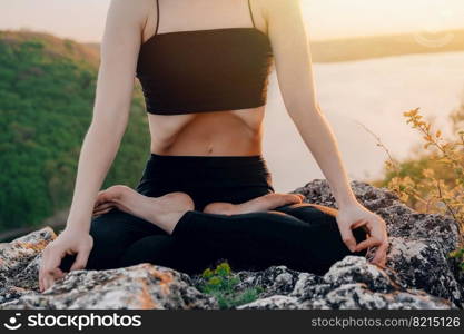 Woman doing yoga belly exercise - Kapalabhati yogic breathing technique. Yogi does uddiyana bandha, sitting in lotus pose on high cliff above water outdoors.Lady breathing, meditating. quality photo. Woman doing yoga belly exercise - Kapalabhati yogic breathing technique. Yogi does uddiyana bandha, while sitting in lotus pose on high cliff above water outdoors.Lady breathing, meditating