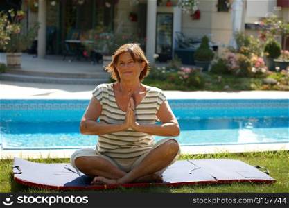 Woman doing yoga by swimming pool