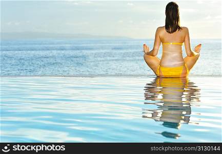 Woman doing yoga exercise at poolside