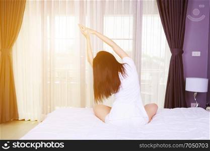 Woman doing yoga exercise on bed in the bedroom
