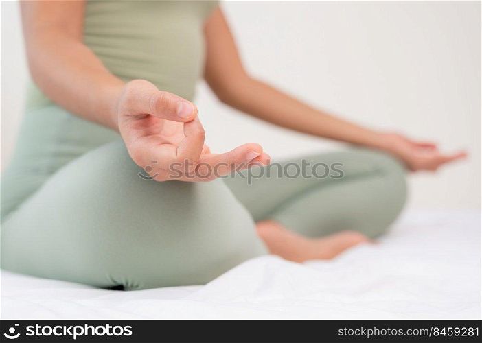 Woman doing yoga exercise on bed with breathing and meditating at home. Morning workout in bedroom. Healthy, relaxation and sport lifestyle.