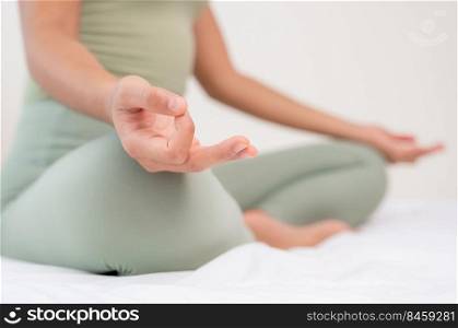 Woman doing yoga exercise on bed with breathing and meditating at home. Morning workout in bedroom. Healthy, relaxation and sport lifestyle.