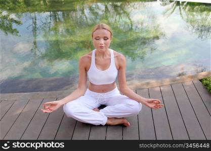 Woman doing yoga exercises on pool deck