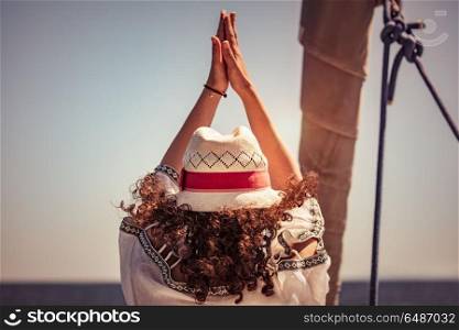 Woman doing yoga exercises, rear view of a female standing in yoga asana on the sailboat among sea, cleansing of aura, meditating on vacation, happy healthy summer holidays. Woman doing yoga exercises