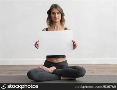 woman doing yoga home holding blank placard