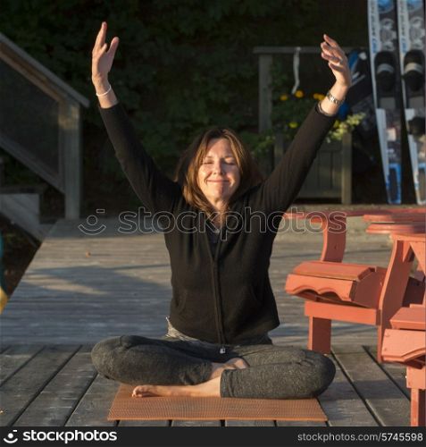 Woman doing yoga on an outdoor deck, Lake of The Woods, Ontario, Canada