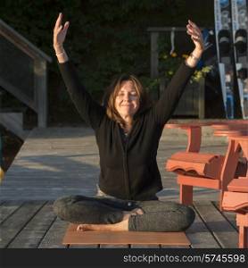 Woman doing yoga on an outdoor deck, Lake of The Woods, Ontario, Canada