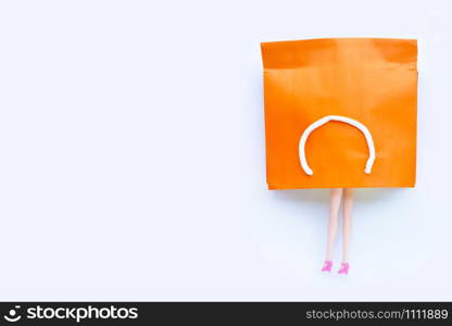 Woman doll legs with paper shopping bag on white background. Copy space