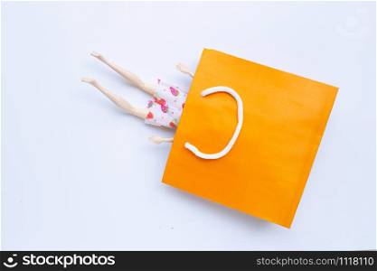 Woman doll legs with paper shopping bag on white background. Copy space