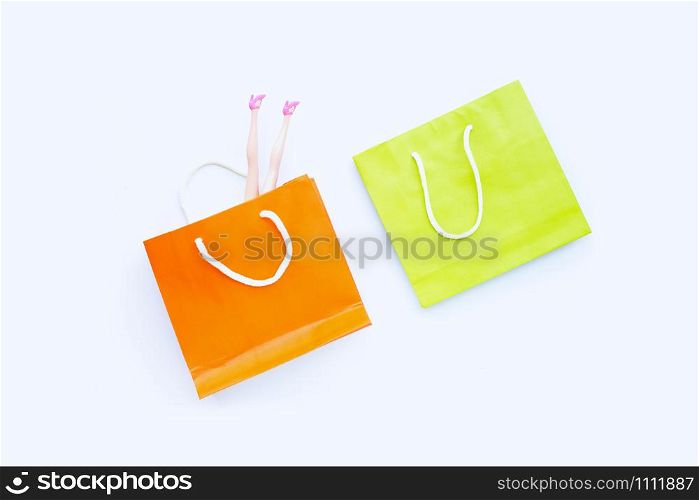 Woman doll legs with paper shopping bags on white background. Top view