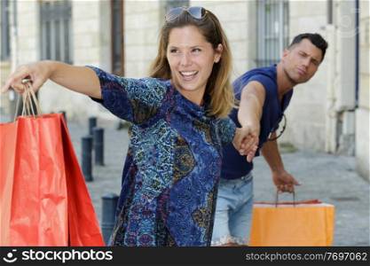 woman dragging her boyfriend to go shopping