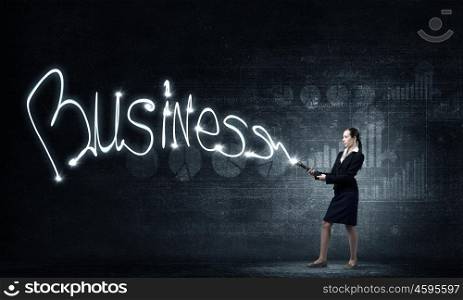 Woman drawing with lantern light. Businesswoman in darkness drawing business word with flashlight