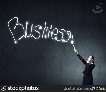 Woman drawing with lantern light. Businesswoman in darkness drawing business word with flashlight
