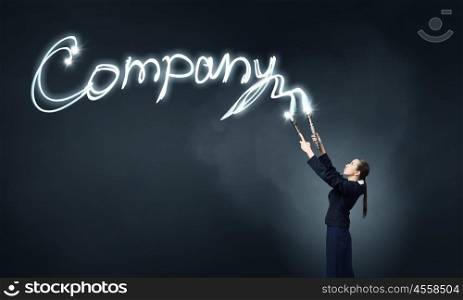 Woman drawing with lantern light. Businesswoman in darkness drawing company word with flashlight