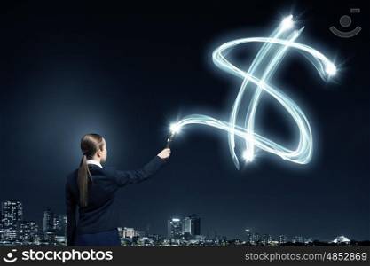 Woman drawing with lantern light. Businesswoman in darkness drawing dollar sign with flashlight