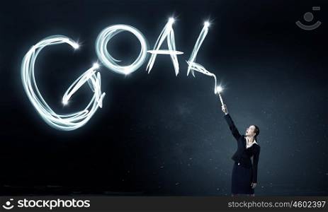 Woman drawing with lantern light. Businesswoman in darkness drawing goal word with flashlight