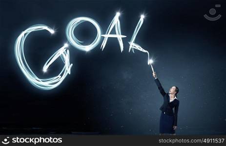 Woman drawing with lantern light. Businesswoman in darkness drawing goal word with flashlight