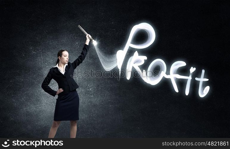 Woman drawing with lantern light. Businesswoman in darkness drawing profit word with flashlight