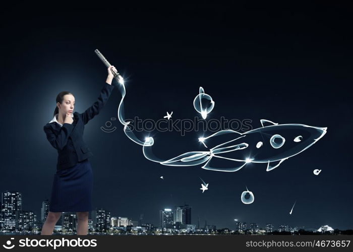 Woman drawing with lantern light. Businesswoman in darkness drawing rocket with flashlight