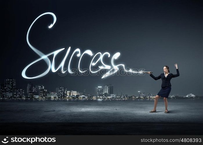 Woman drawing with lantern light. Businesswoman in darkness drawing success word with flashlight