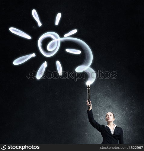 Woman drawing with lantern light. Businesswoman in darkness drawing sun with flashlight