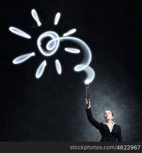 Woman drawing with lantern light. Businesswoman in darkness drawing sun with flashlight