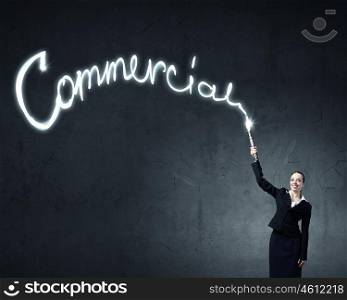 Woman drawing with lantern light. Businesswoman in darkness drawing word commercial with flashlight
