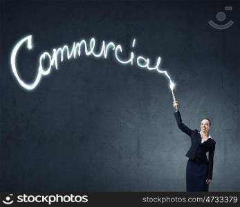 Woman drawing with lantern light. Businesswoman in darkness drawing word commercial with flashlight