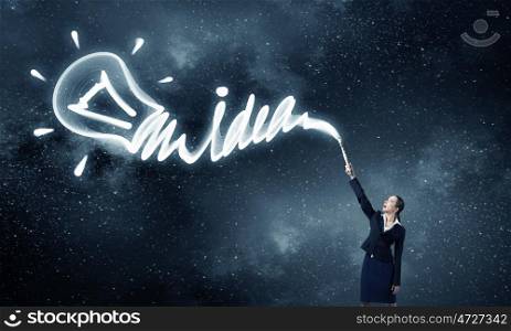 Woman drawing with lantern light. Businesswoman in darkness drawing word idea with flashlight