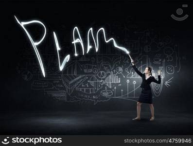 Woman drawing with lantern light. Businesswoman in darkness drawing word plan with flashlight