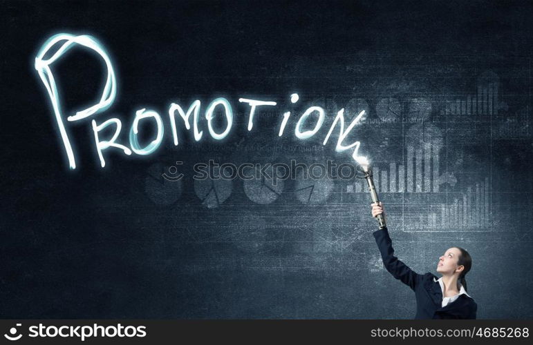 Woman drawing with lantern light. Businesswoman in darkness drawing word promotion with flashlight